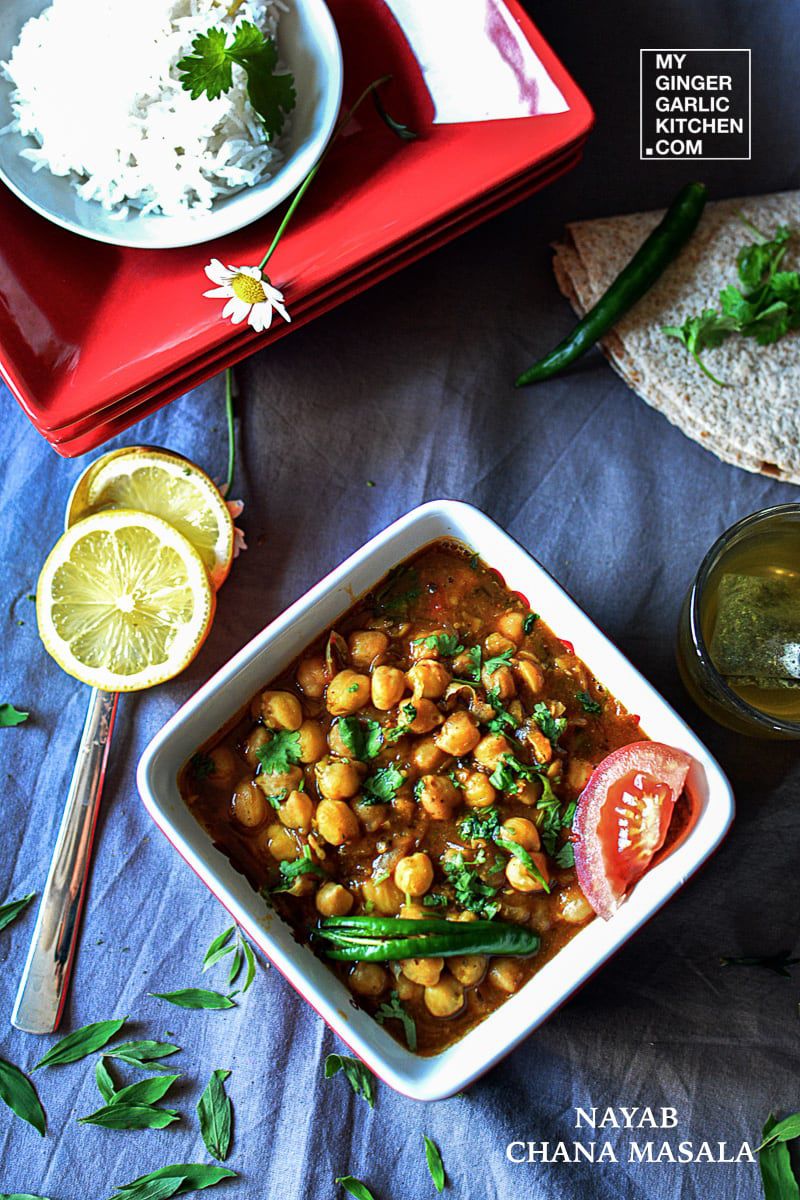 a bowl of chana masala curry with a spoon and a plate of rice