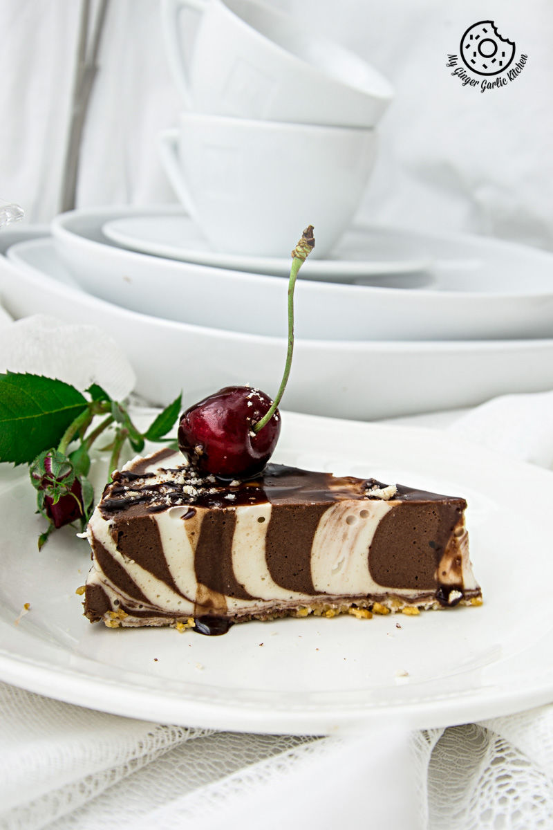 a piece of no bake zebra cheesecake on a plate with a cherry on top