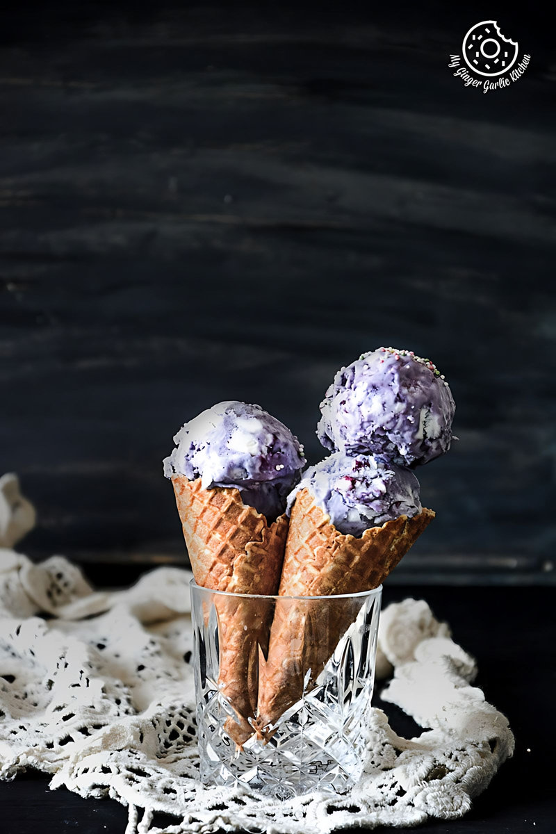 two cones of no churn vegan coconut blueberry ice cream in a glass on a doily