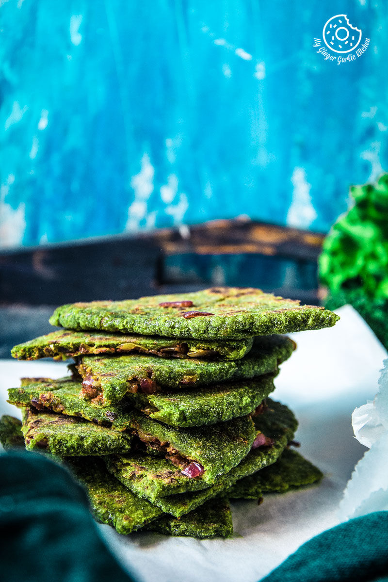 there are a stack of oats green parathas on a plate with a bowl of lettuce