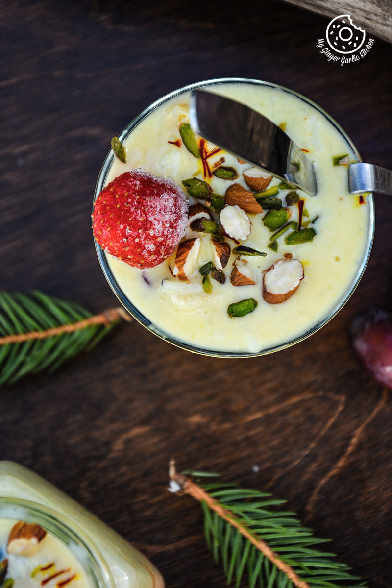 a glass of oliya indian version of greek style rice pudding with fruit and nuts on a table