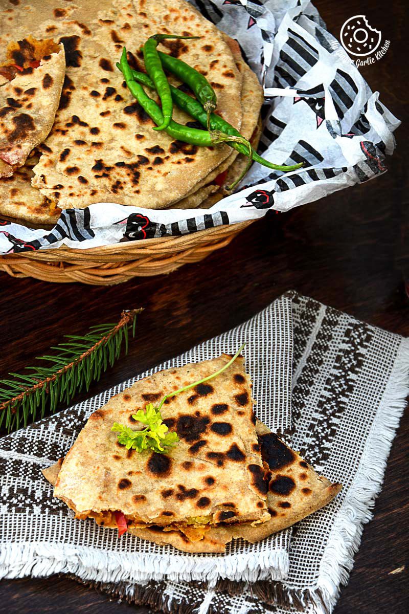 a basket of pepper onion potato paratha with green chilies on a table