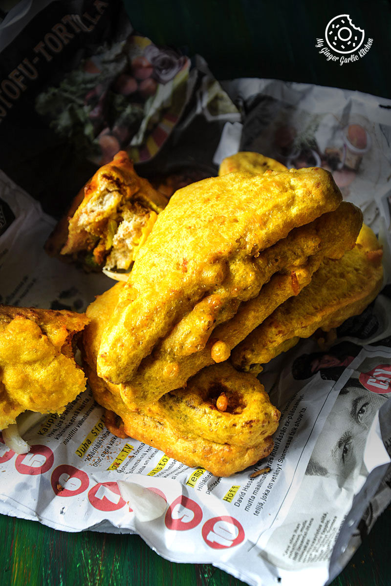 some potato stuffed bread pakoras that is on a newspaper on a table