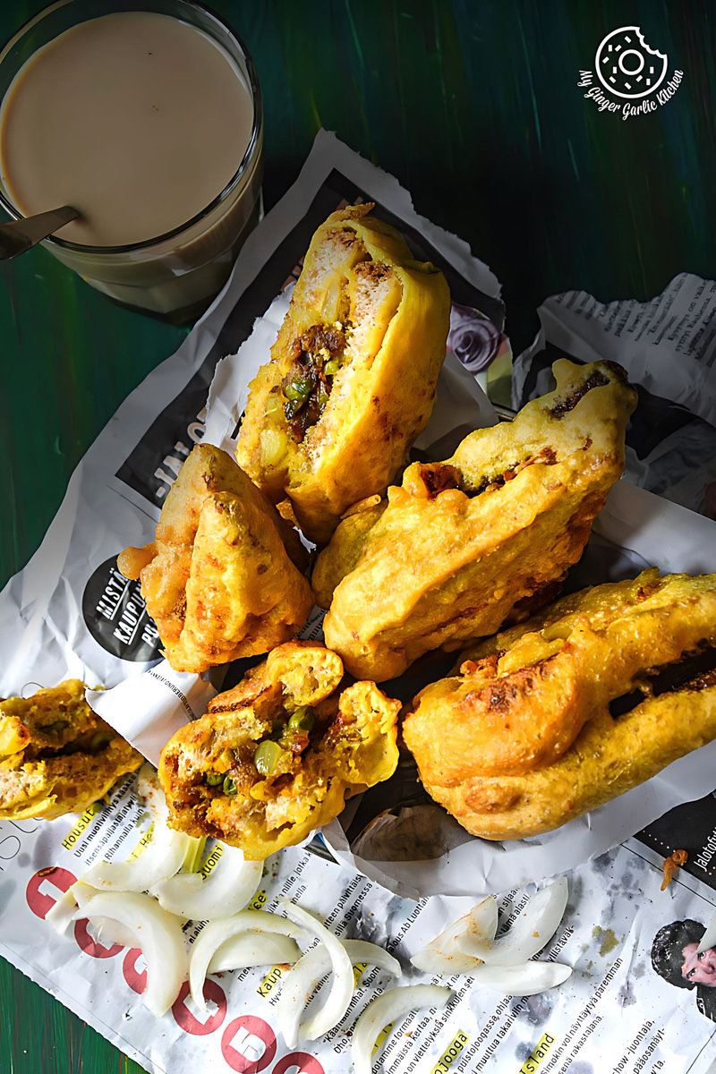 some potato stuffed bread pakoras on a newspaper with a cup of coffee