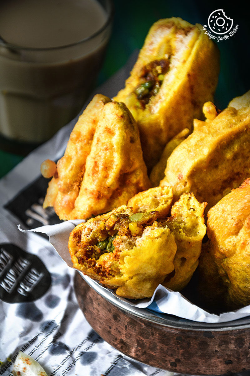 a basket of fried potato stuffed bread pakoras on a table with a cup of coffee