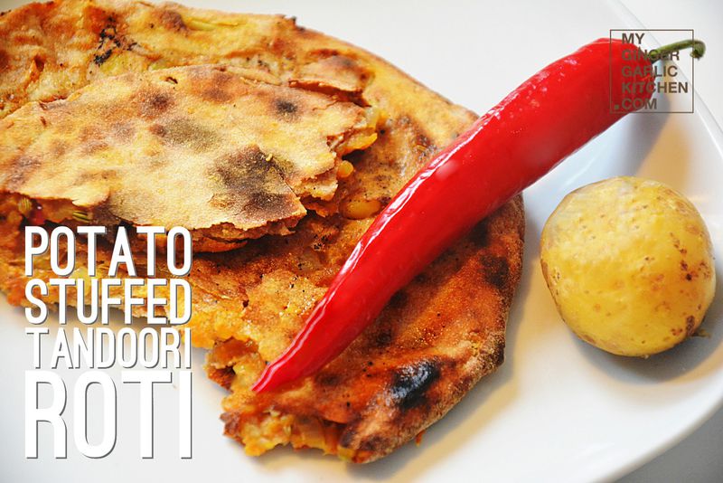 a plate of potato stuffed tandoori roti with a potato and a chili on it