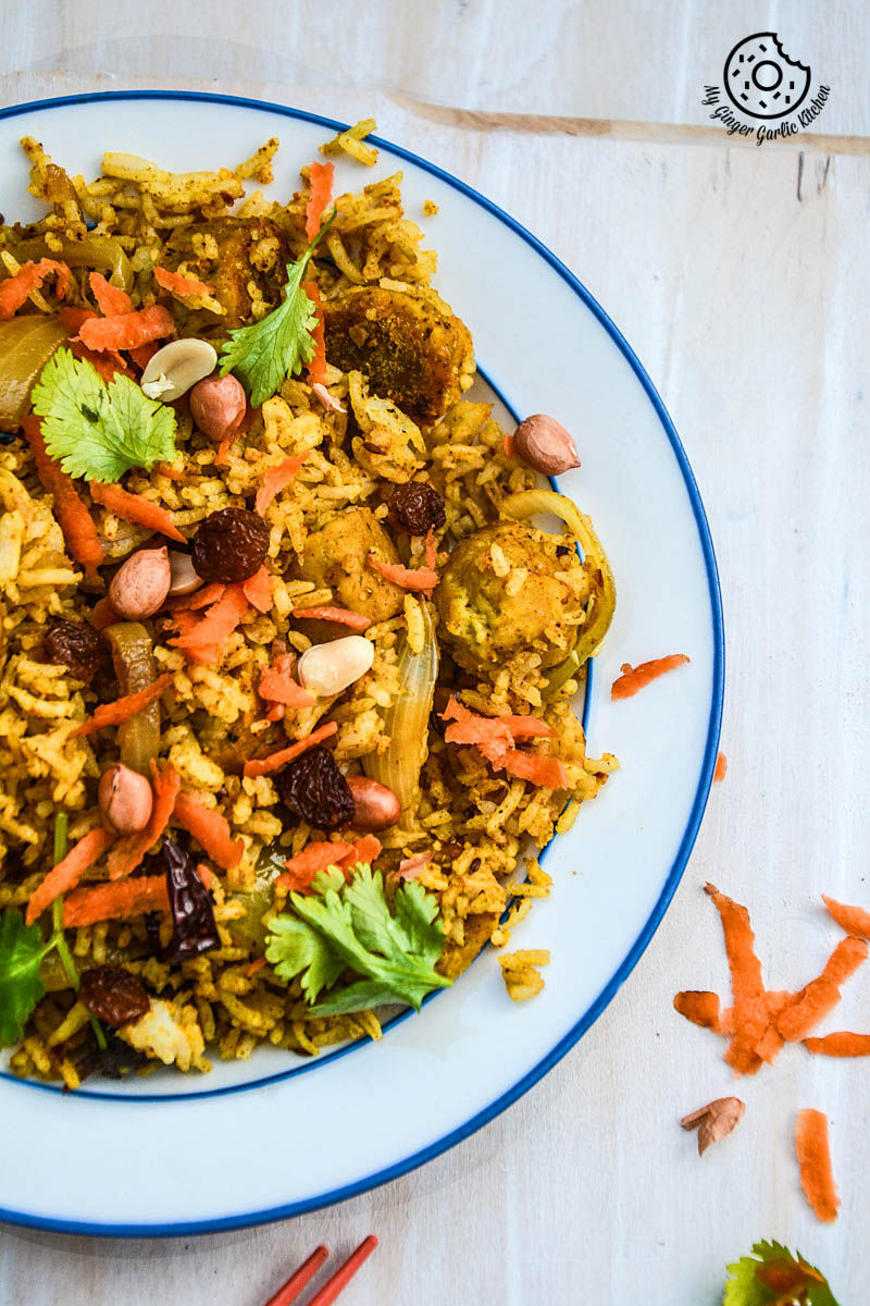 there is a plate of rajasthani gatta pulav with carrots and nuts on it