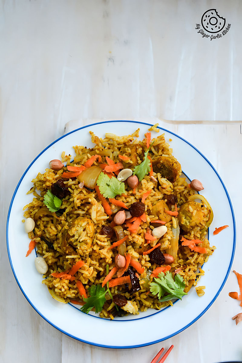 there is a plate of rajasthani gatta pulav with carrots and nuts on it