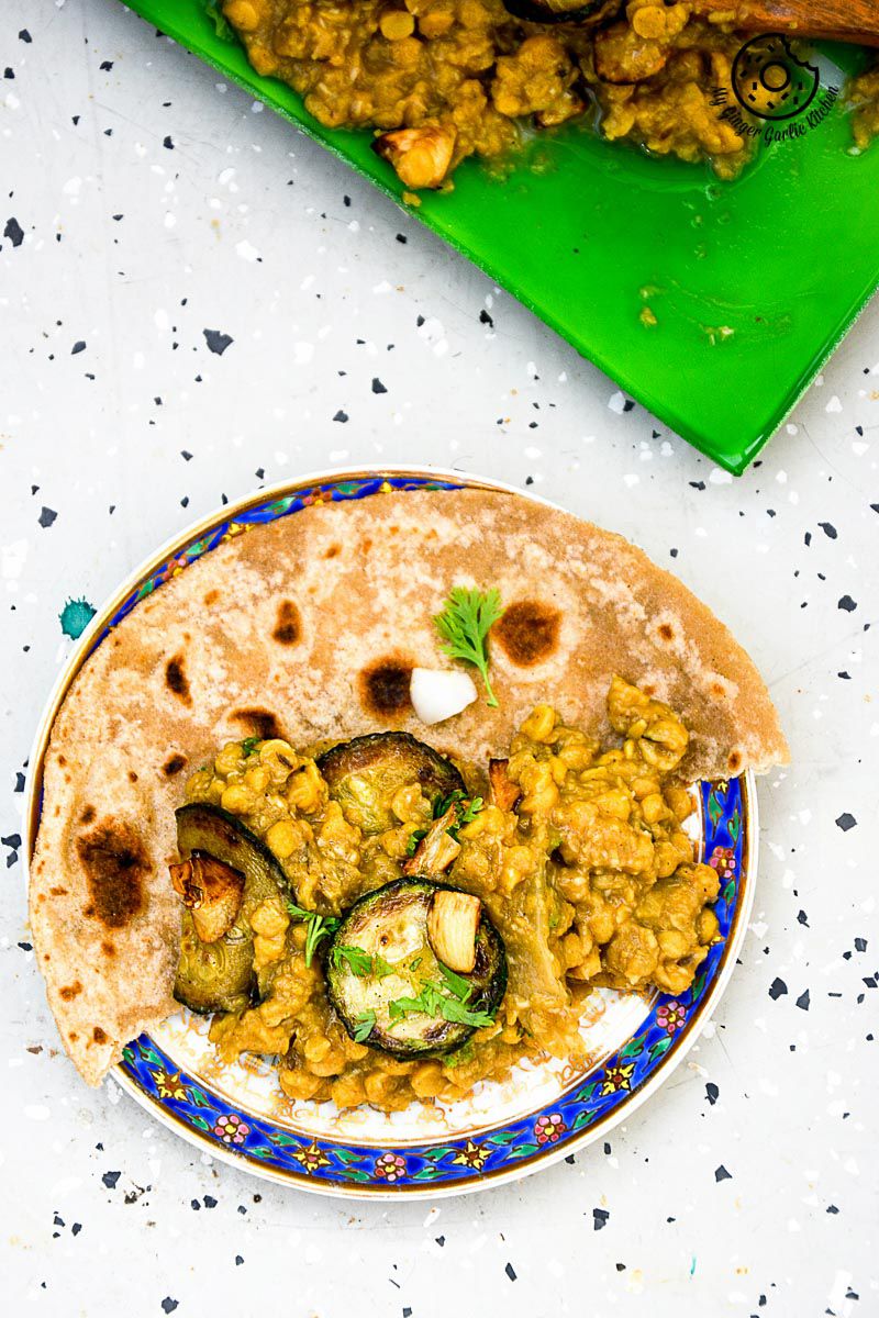 a plate of roasted zucchini garlic with spiced chana dal with paratha that is on a table
