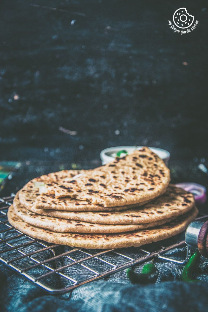 three sev stuffed parathas stacked on a cooling rack