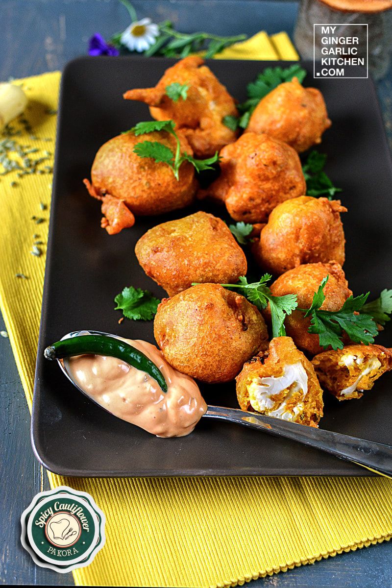 a plate of spicy cauliflower pakoras sprinkled with cilantro, sauce and a spoon