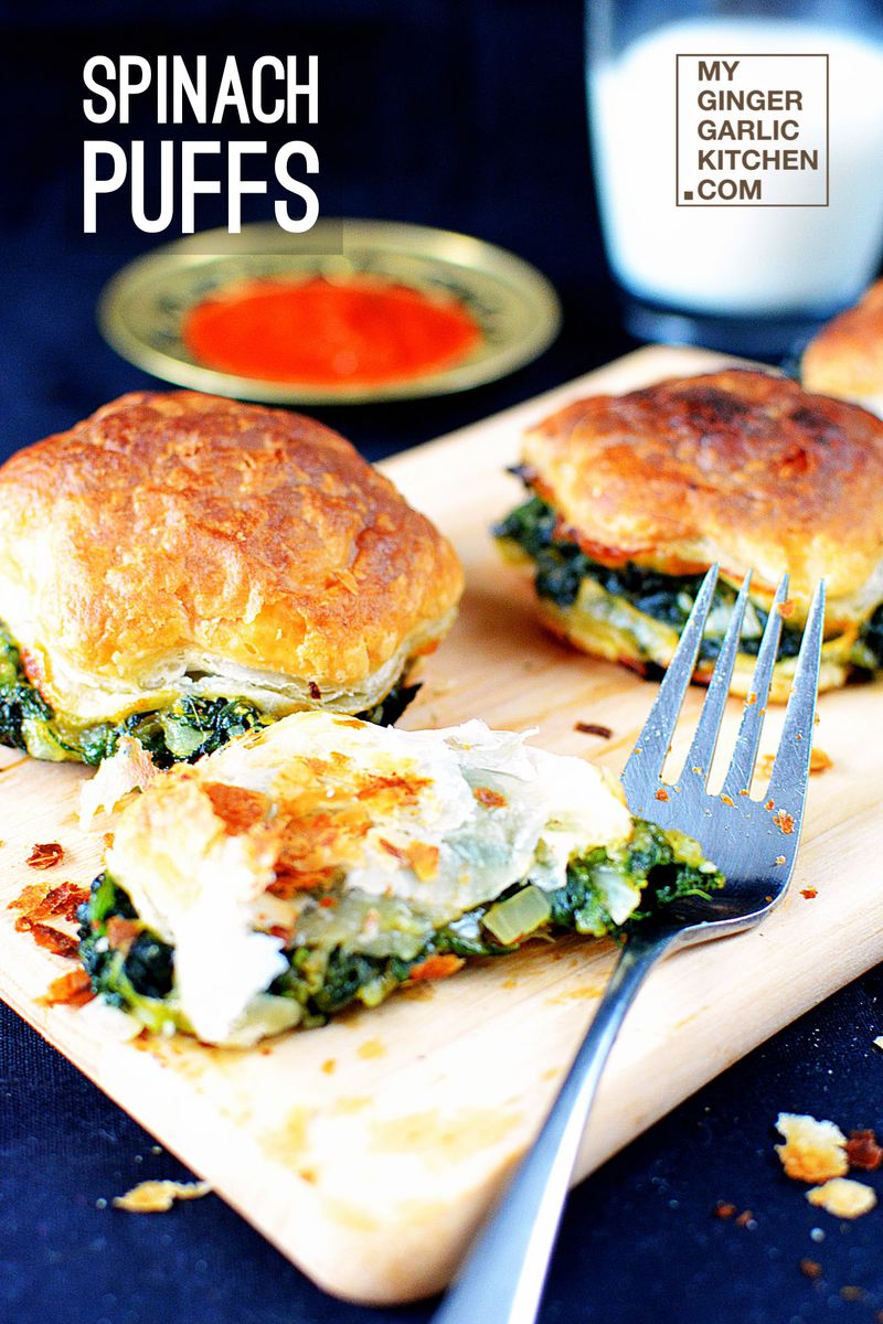 three spinach puffs on a cutting board with a fork