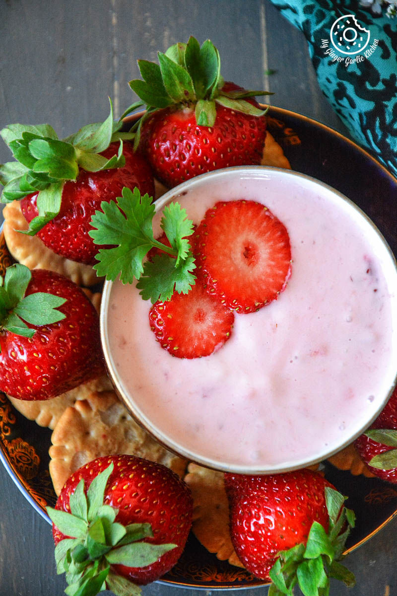 a bowl of strawberry cheesecake dip with fresh strawberries and crackers on a plate