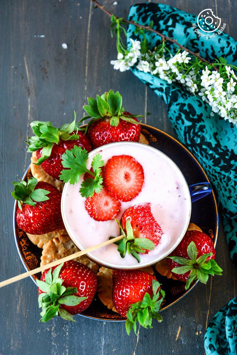a bowl of strawberry cheesecake dip with a skewer sticking out of it