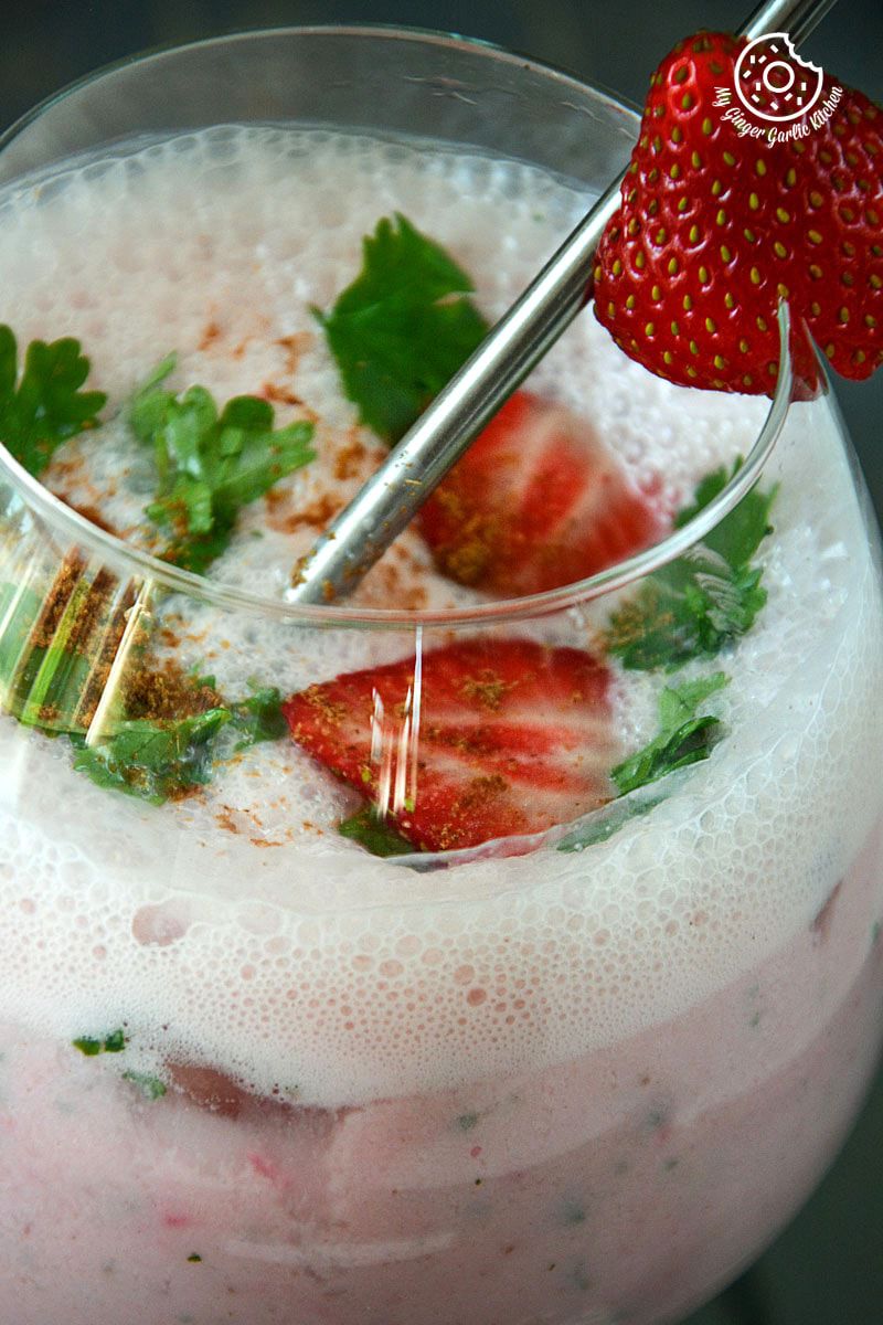 a glass of a strawberry masala chaas with strawberries and mint
