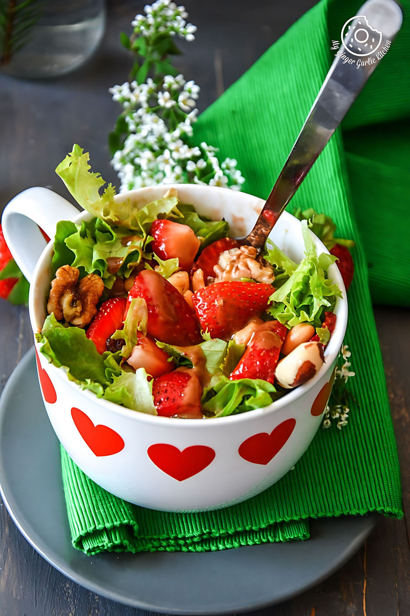 a bowl of summer berry salad with salted with peanuts and walnuts in it on a plate
