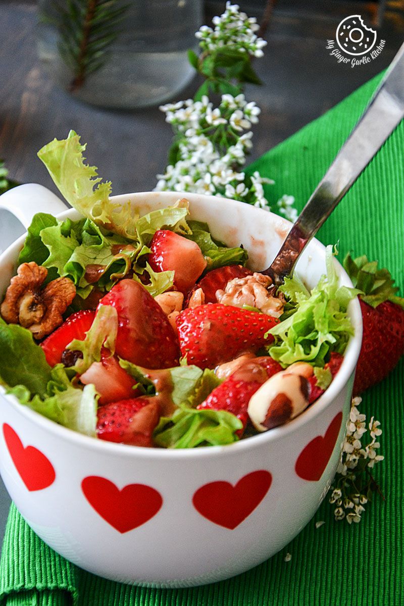 a bowl of summer berry salad with salted with peanuts and walnuts in it