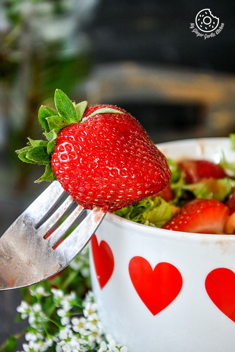 a fork with a strawberry on it in a bowl