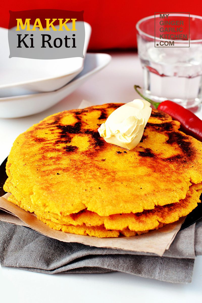 a stack of makki ki roti with butter on a plate and a glass of water
