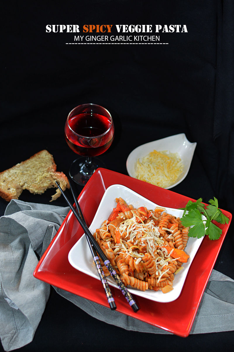 a plate of super spicy veggie pasta and a glass of wine on a table