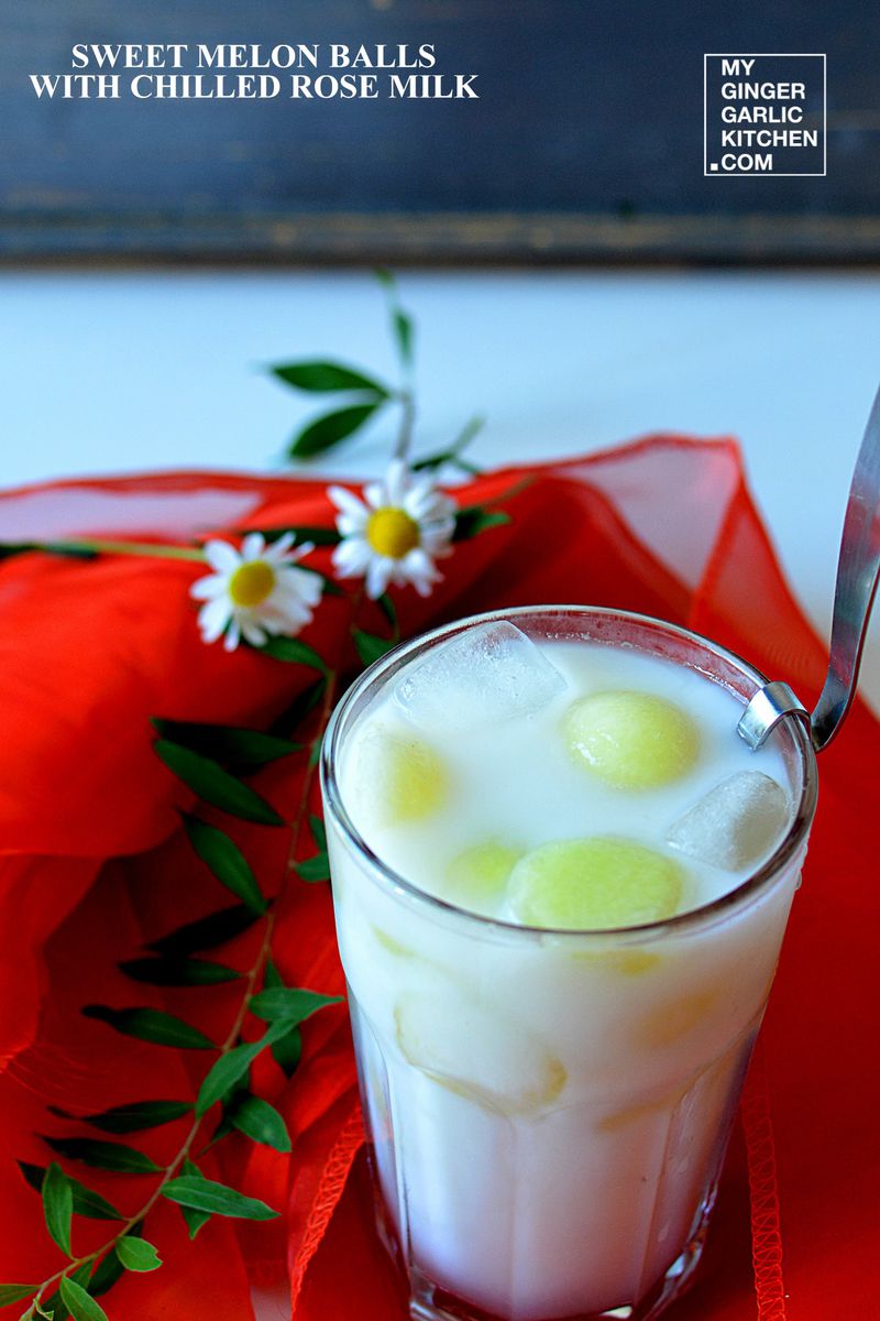 a glass of chilled rose milk with sweet melon balls some ice and some flowers