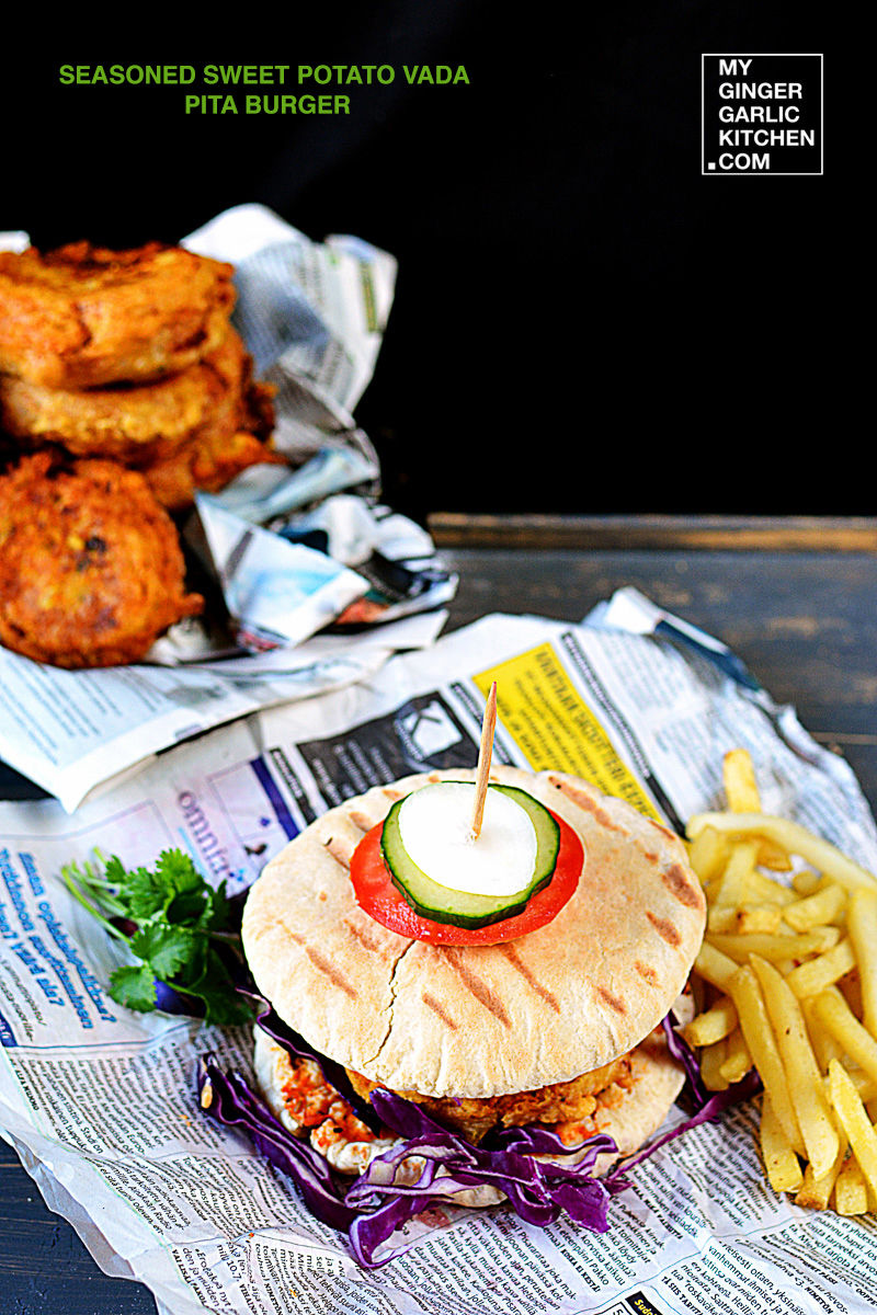 a sweet potato vada pita burger and french fries on a newspaper on a table