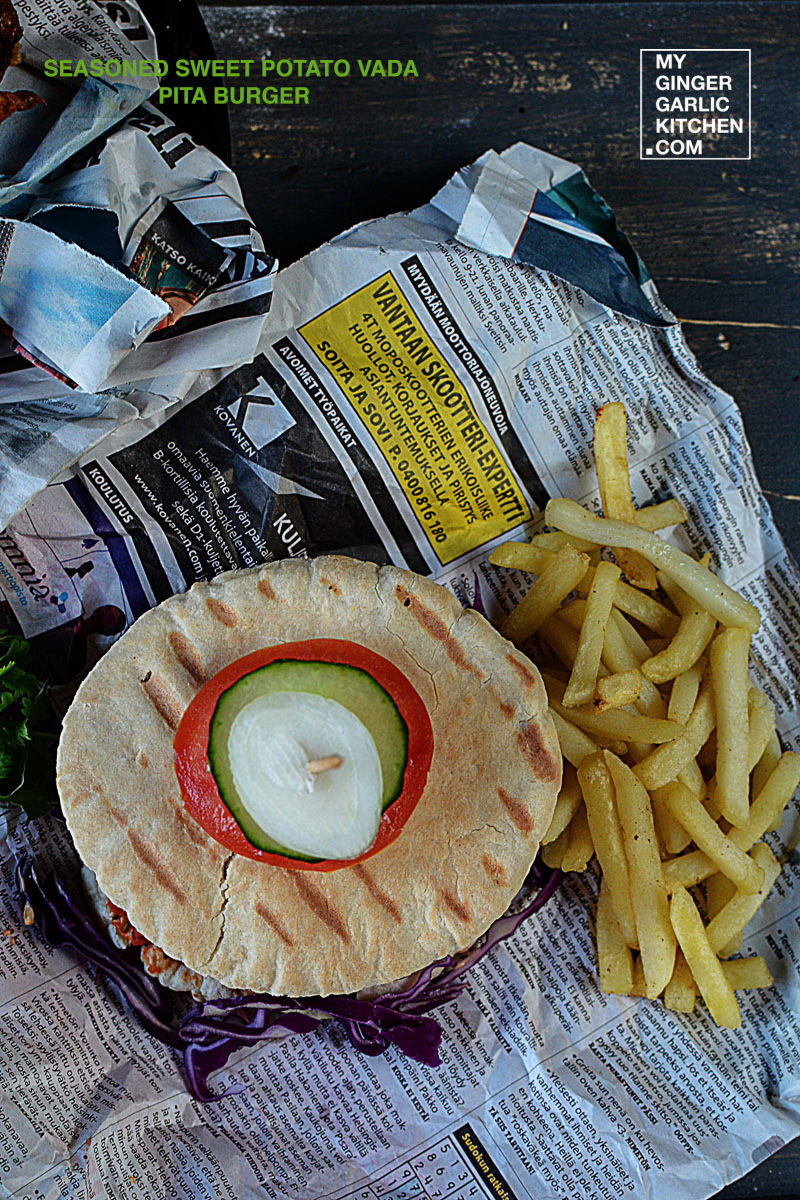 newspaper on the table with a sweet potato vada pita burger and french fries