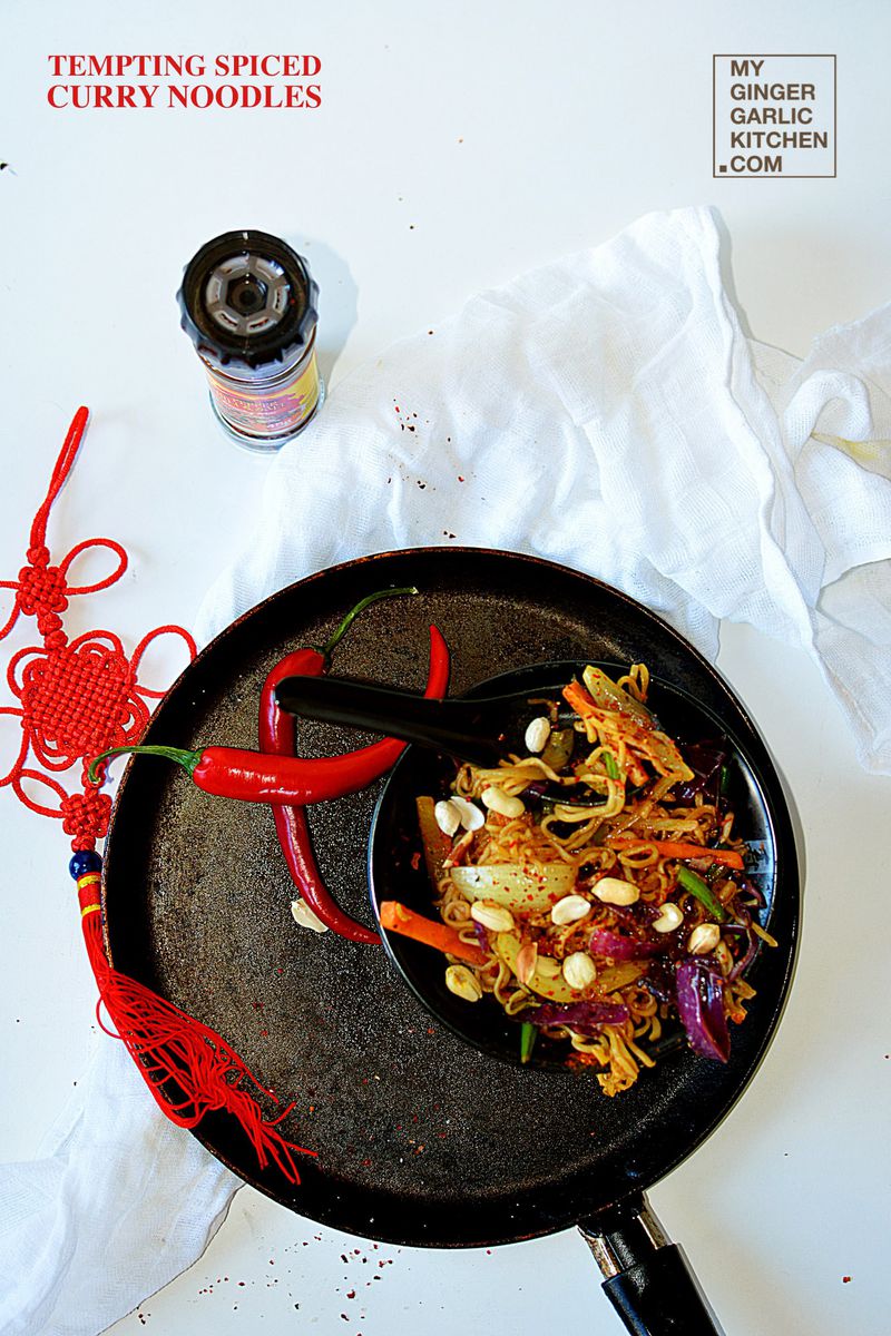 a bowl with spiced curry noodles and vegetables in it on a table