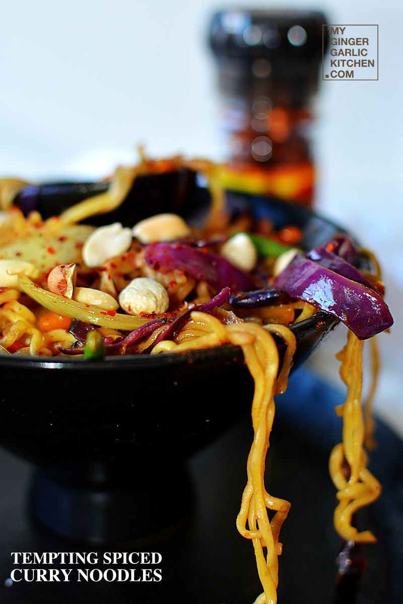 a bowl of spiced curry noodles with vegetables and nuts in it