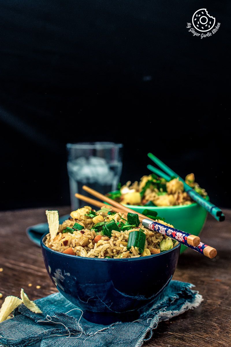 a bowl of thai pineapple fried rice vegan with chopsticks and a glass of water