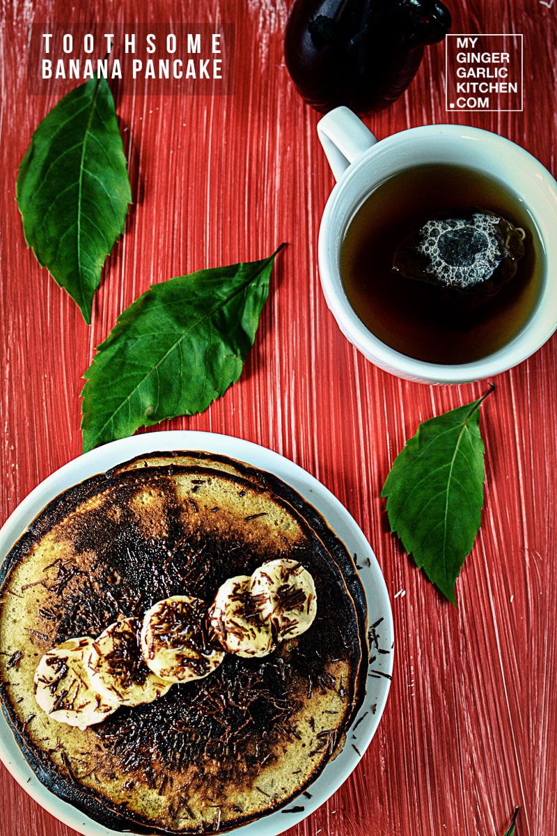 a plate of banana pancakes with bananas and a cup of tea