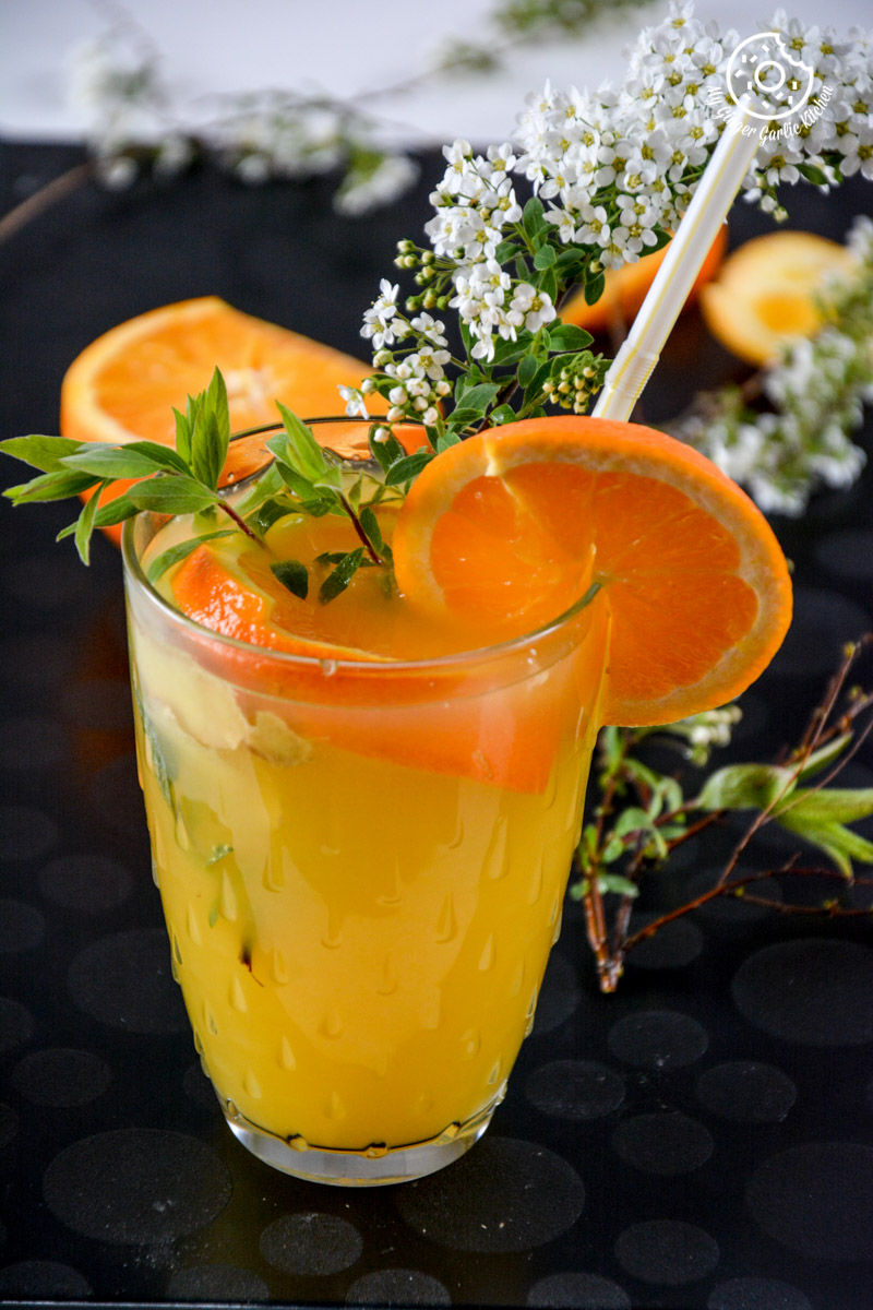 a glass of virgin ginger mimosa with a straw and flowers