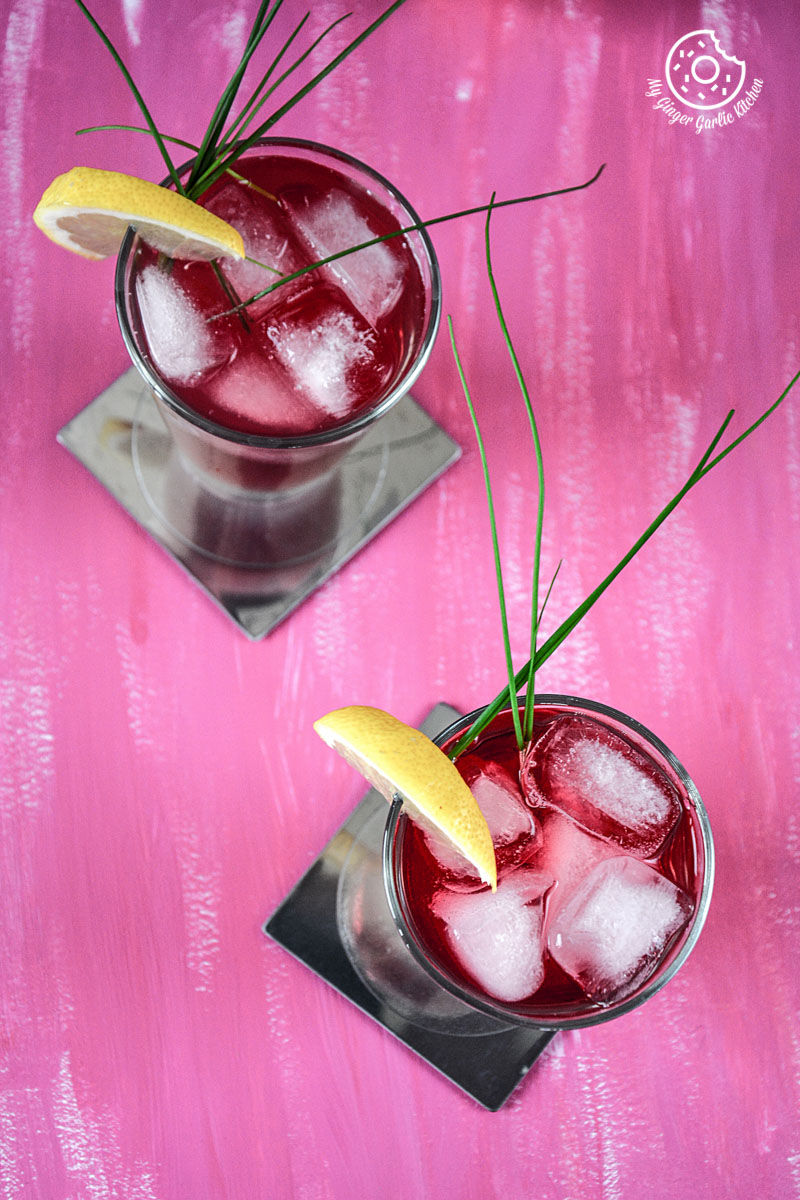 two glasses of watermelon lemonade with lemon wedges on the top