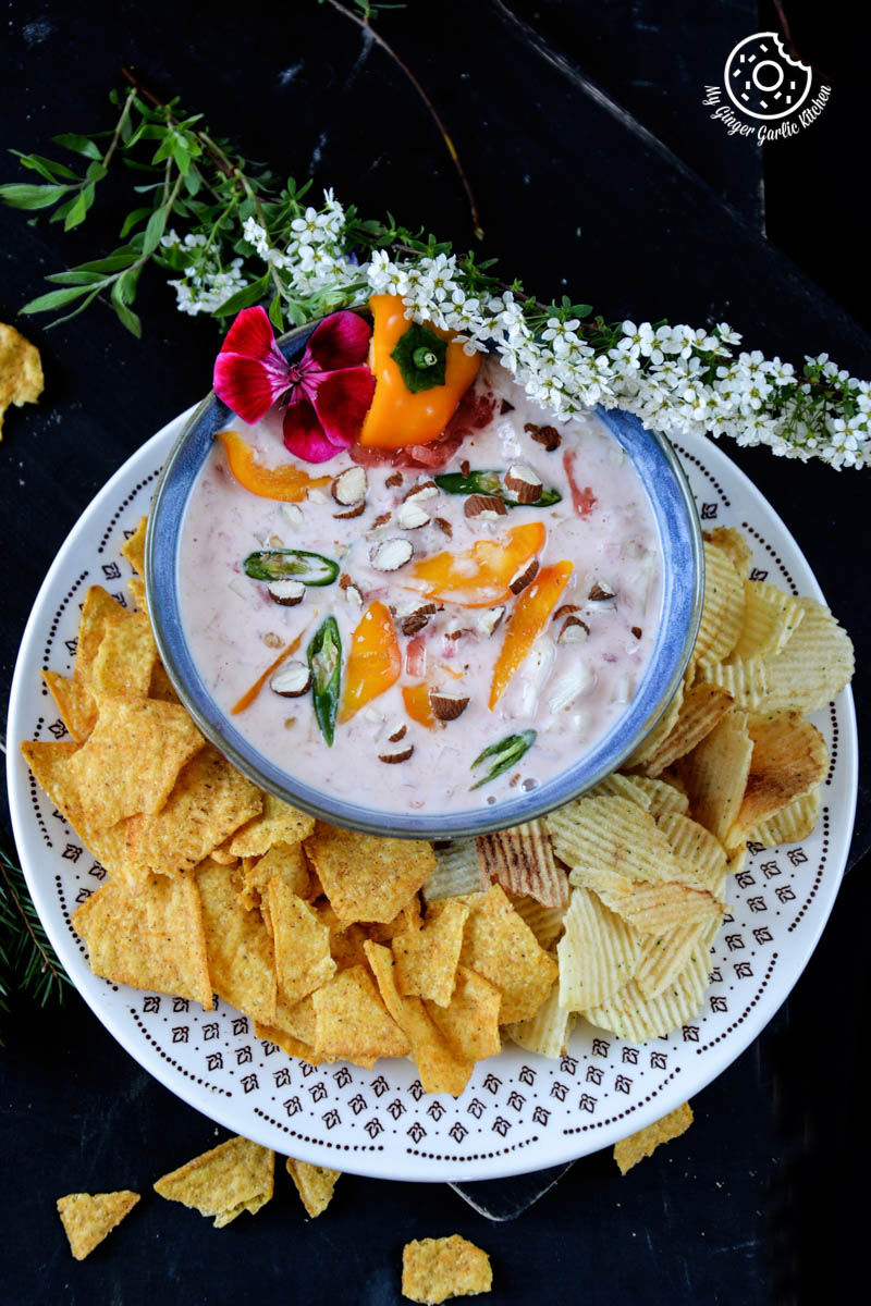 a bowl of watermelon onion raita with chips and flowers on the side
