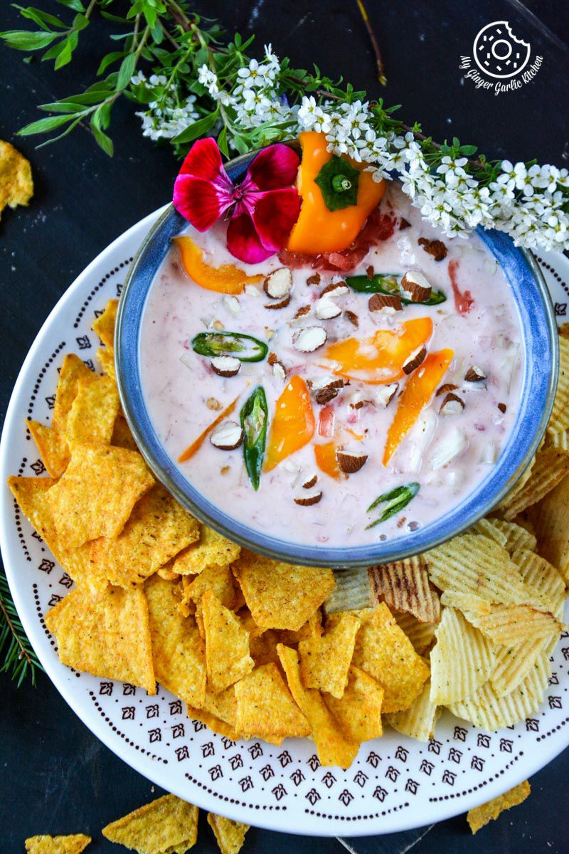 a bowl of watermelon onion raita with chips and flowers on the side