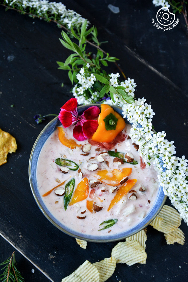 a bowl of watermelon onion raita with chips and flowers on the table