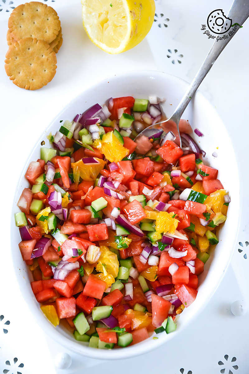 a bowl of watermelon orange salsa with a spoon in it