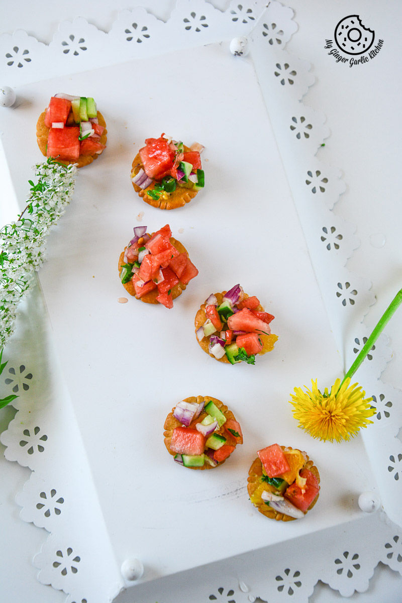 small watermelon orange salsa appetizers on a white plate with a flower