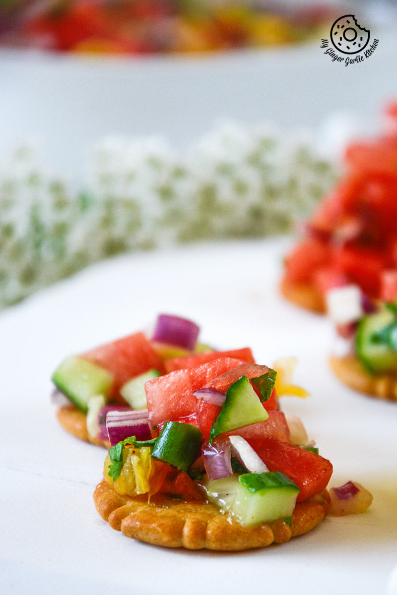 two small crackers with watermelon orange salsa on them on a plate