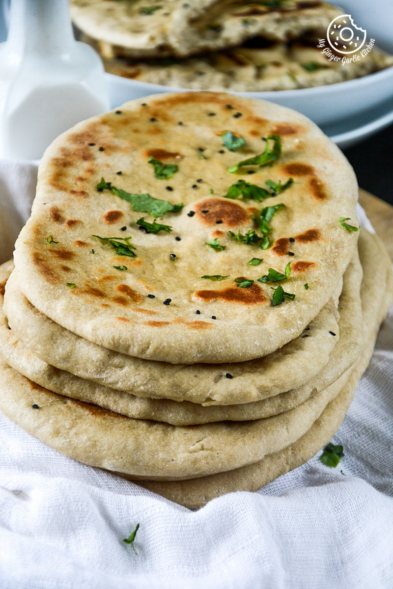 a stack of yeast free whole wheat naans with herbs and herbs on a white napkin