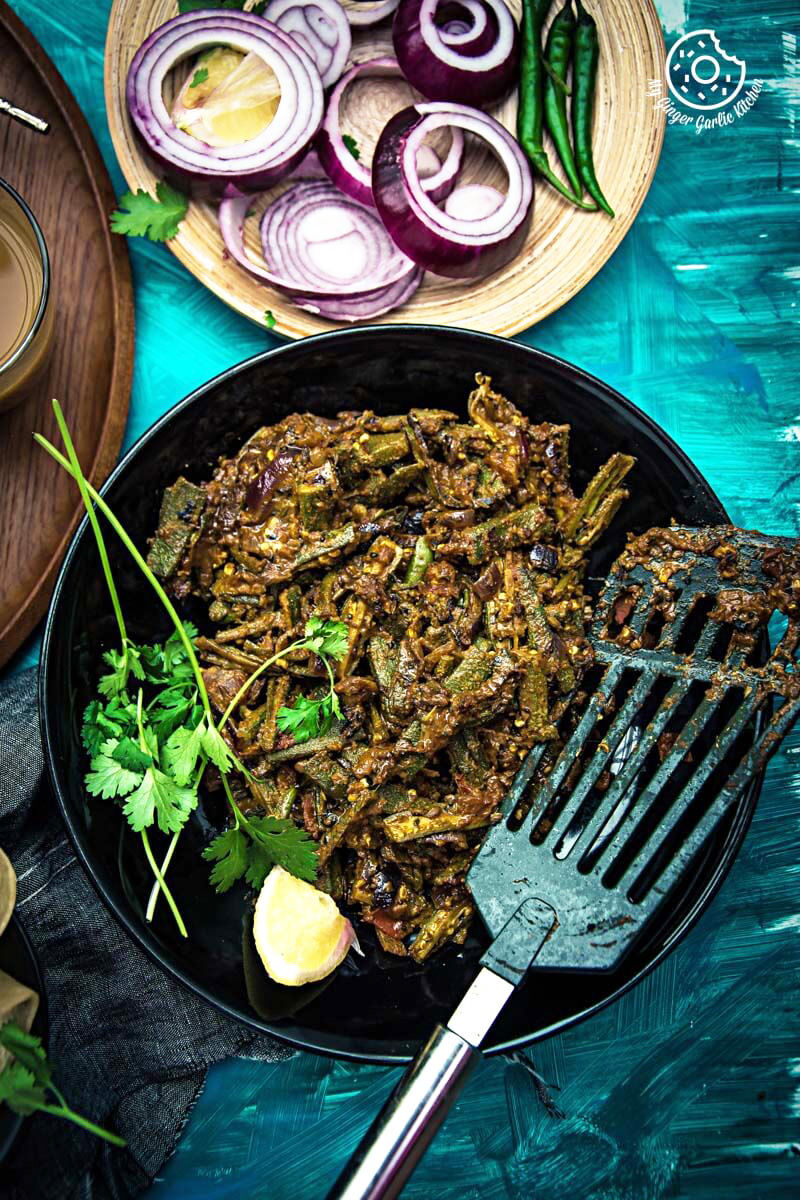 a plate of achaari dahi bhindi with some sliced onions on a table