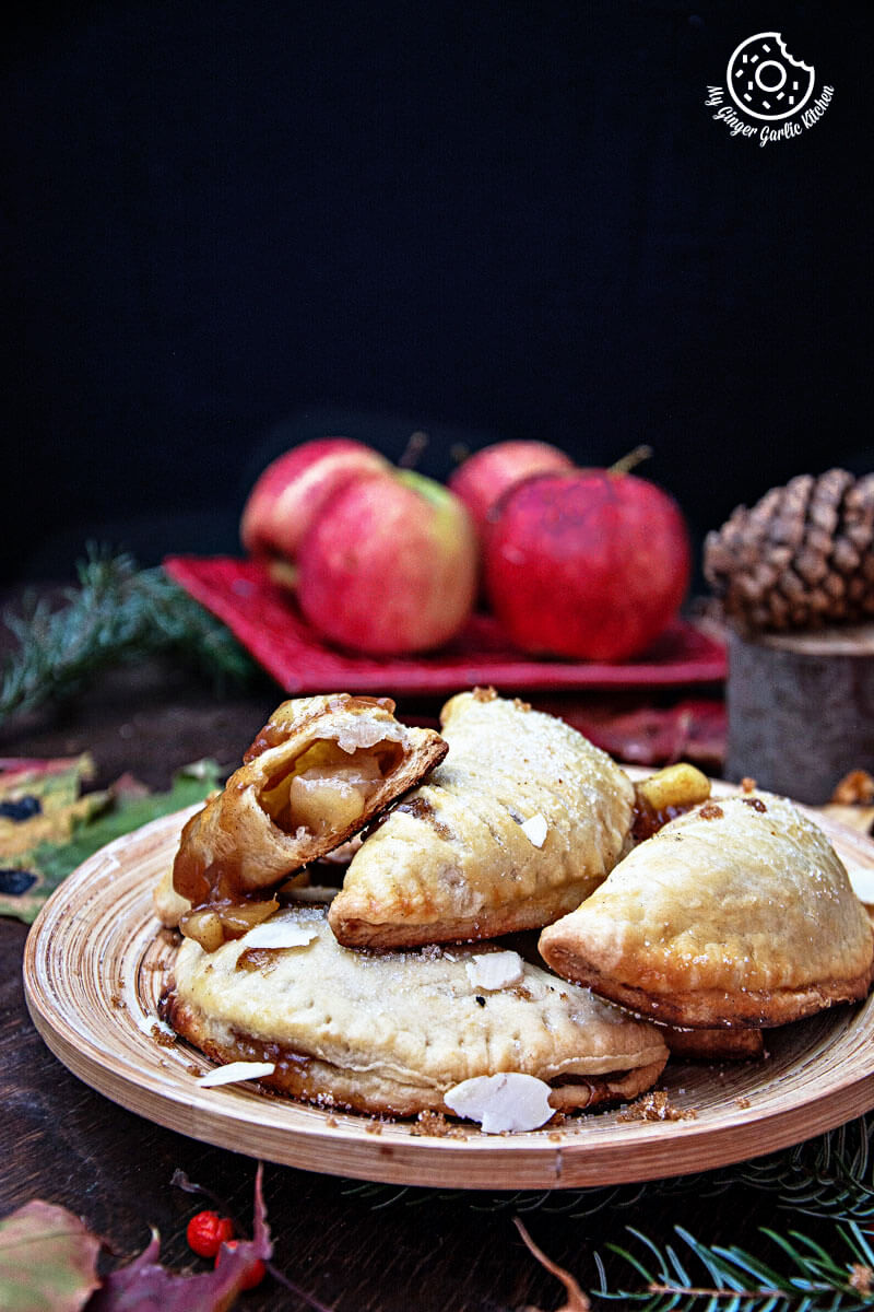a plate of apple hand pies with apples in the background