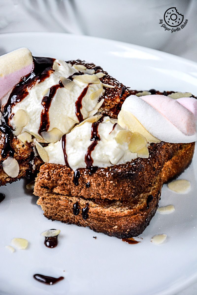 a plate with a banana nutella stuffed cinnamon maple toast whipped cream and chocolate sauce on it