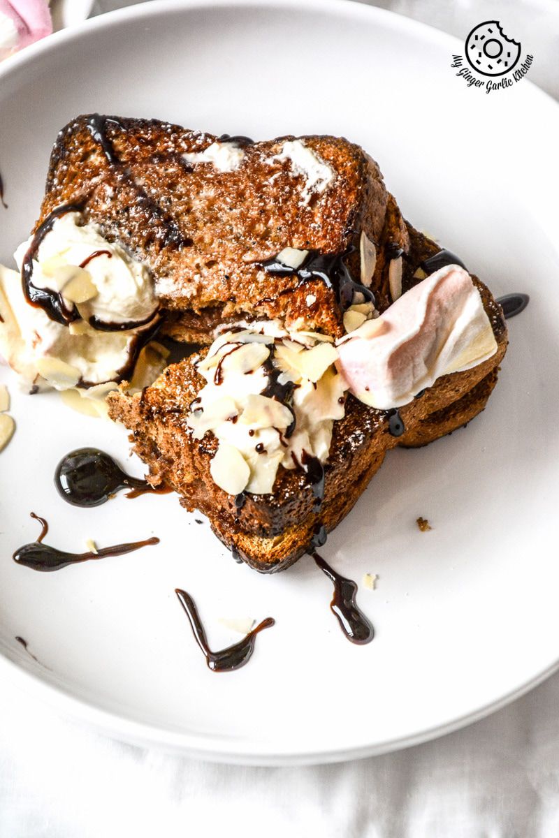 a plate with a piece of a banana nutella stuffed cinnamon maple toast whipped cream and chocolate sauce on it on it