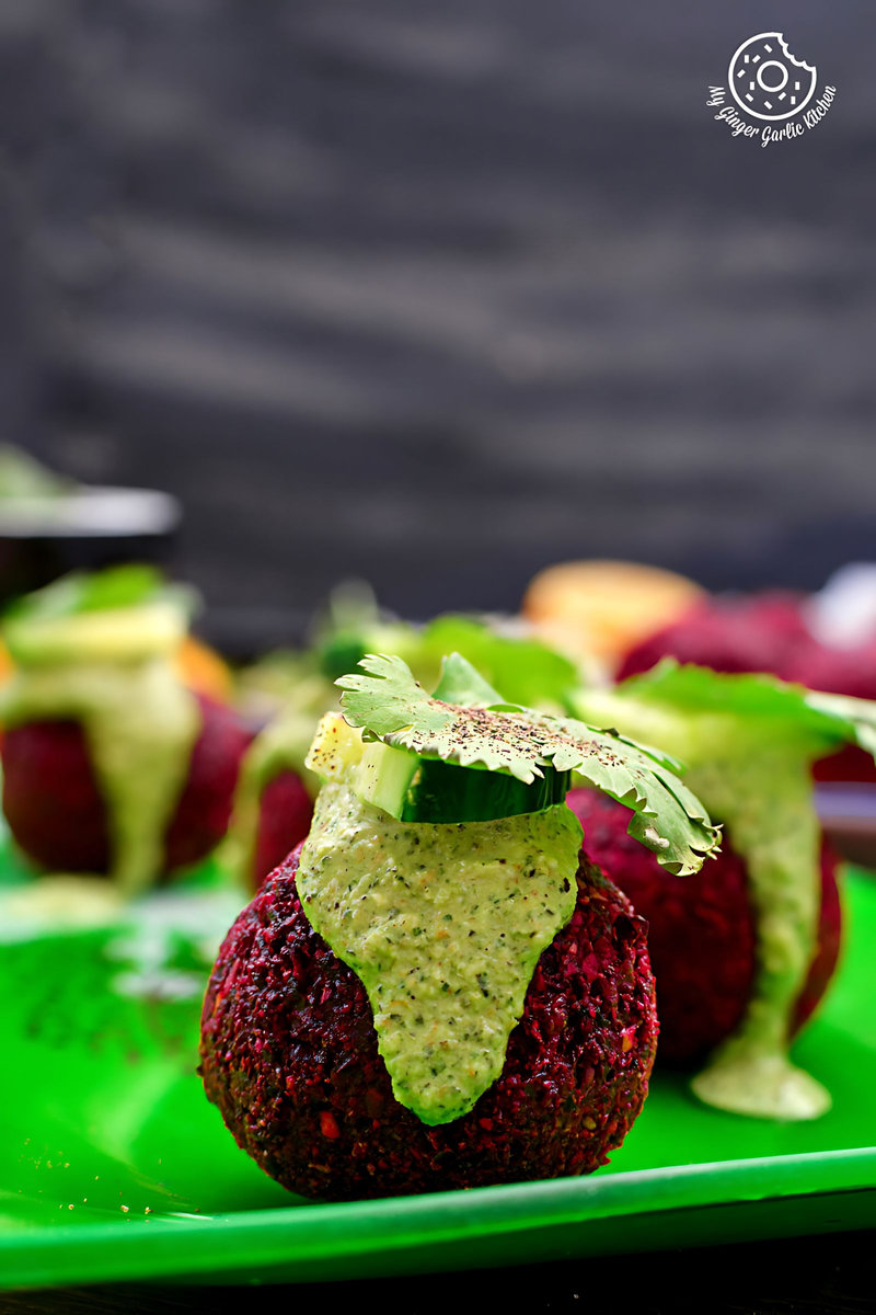 some beet falafel with green tahini dip on a green plate
