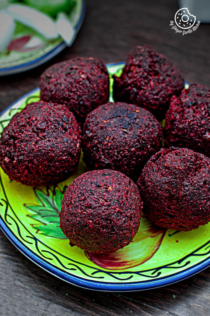 a plate of beet falafels on a table with a plate of other food