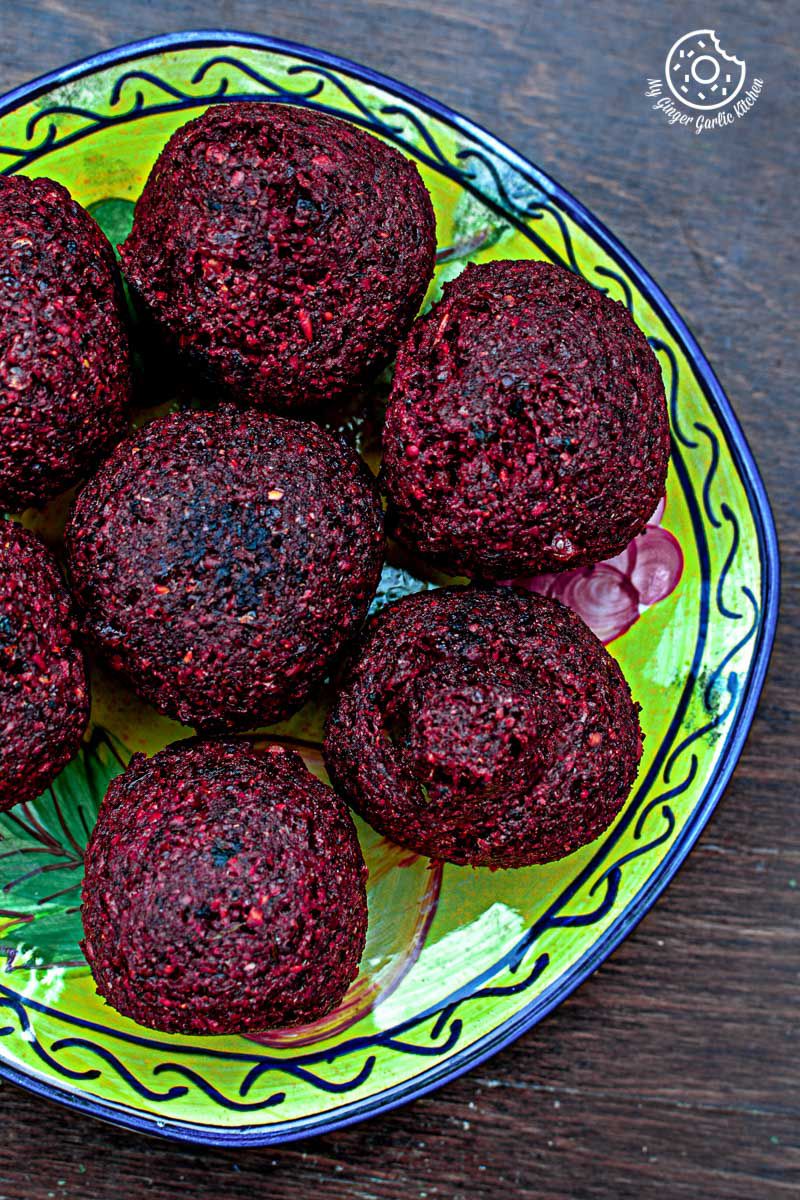 a plate of red beet falafels on a table with a plate of other food