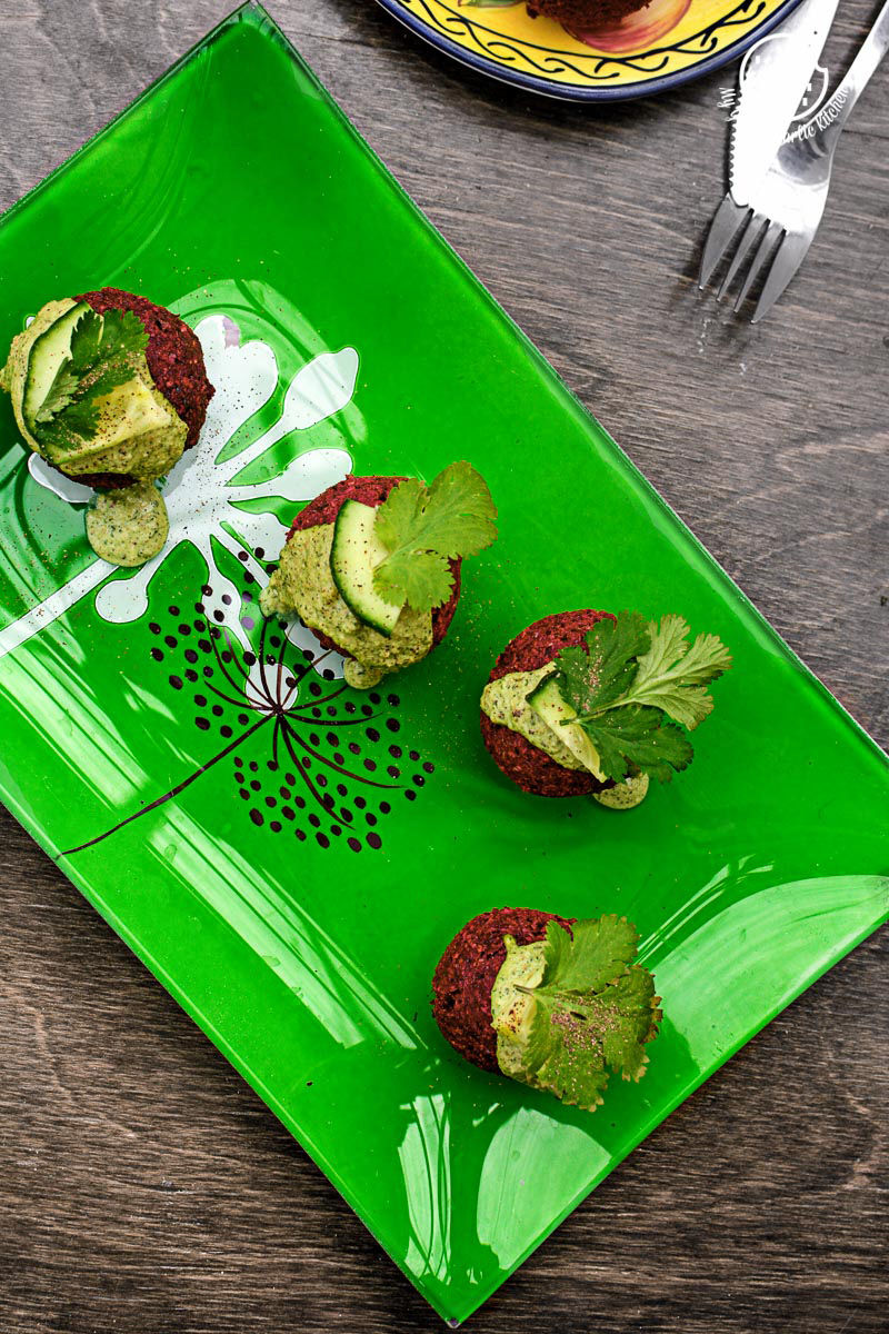 four beet falafel with green tahini dip on a green plate