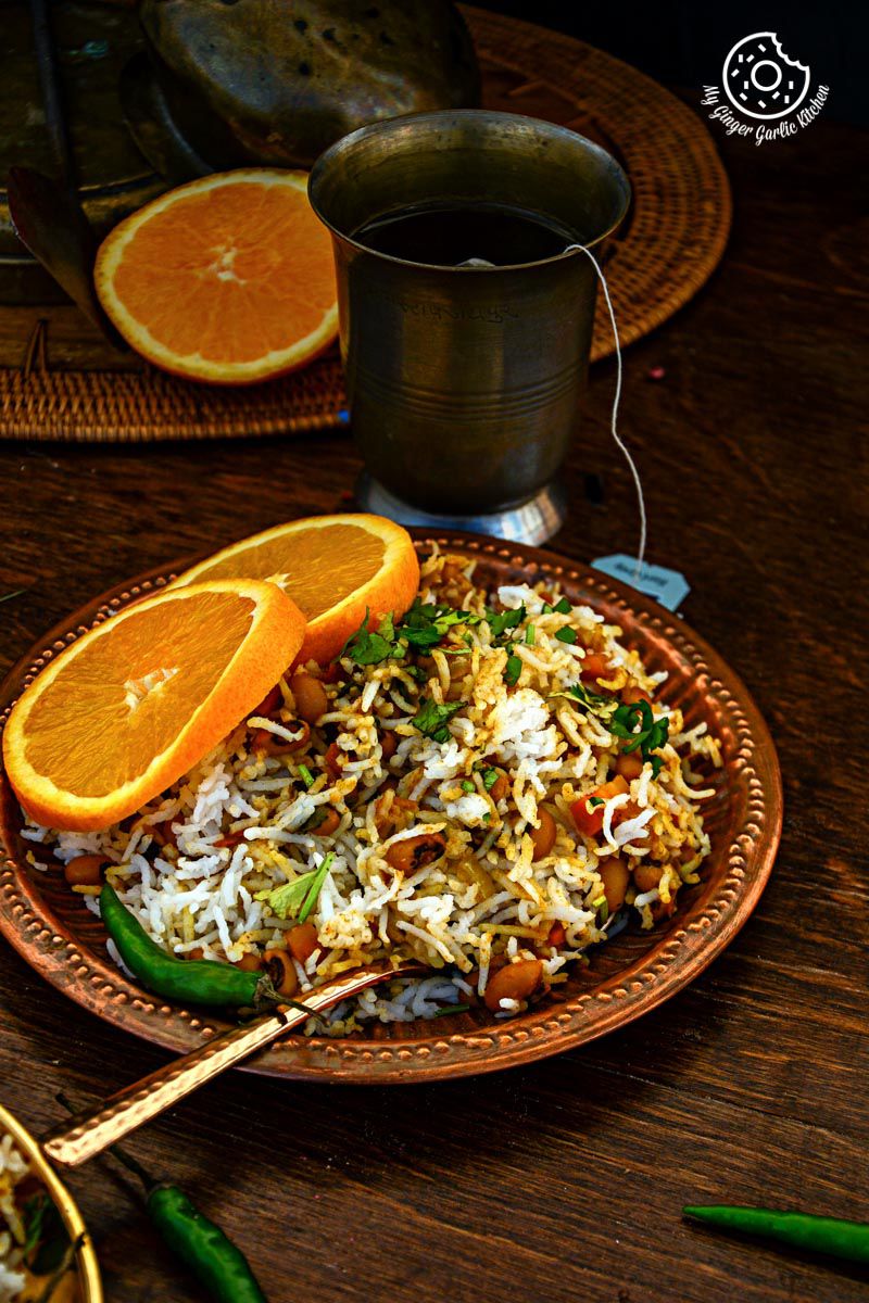 a plate of black eyed bean carrot biryani and orange slices on a table