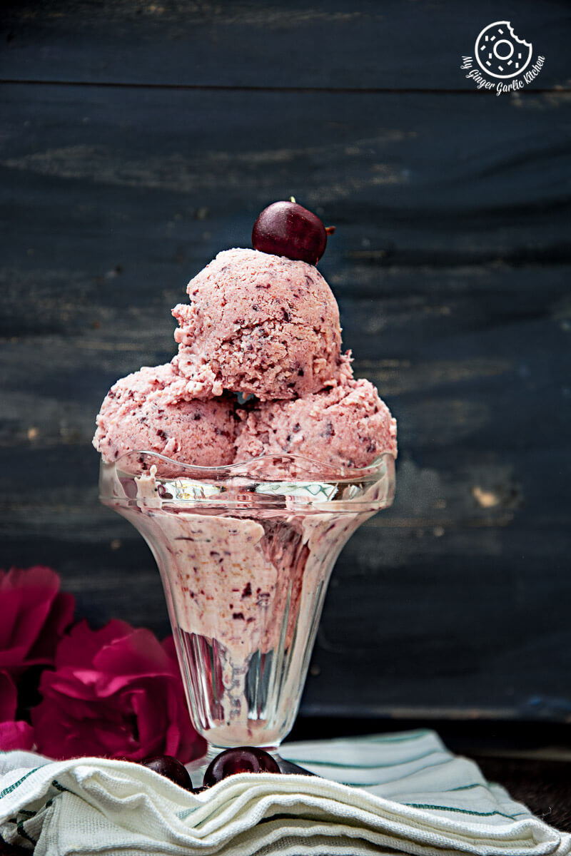 a glass bowl with a cherry lassi ice cream and cherries